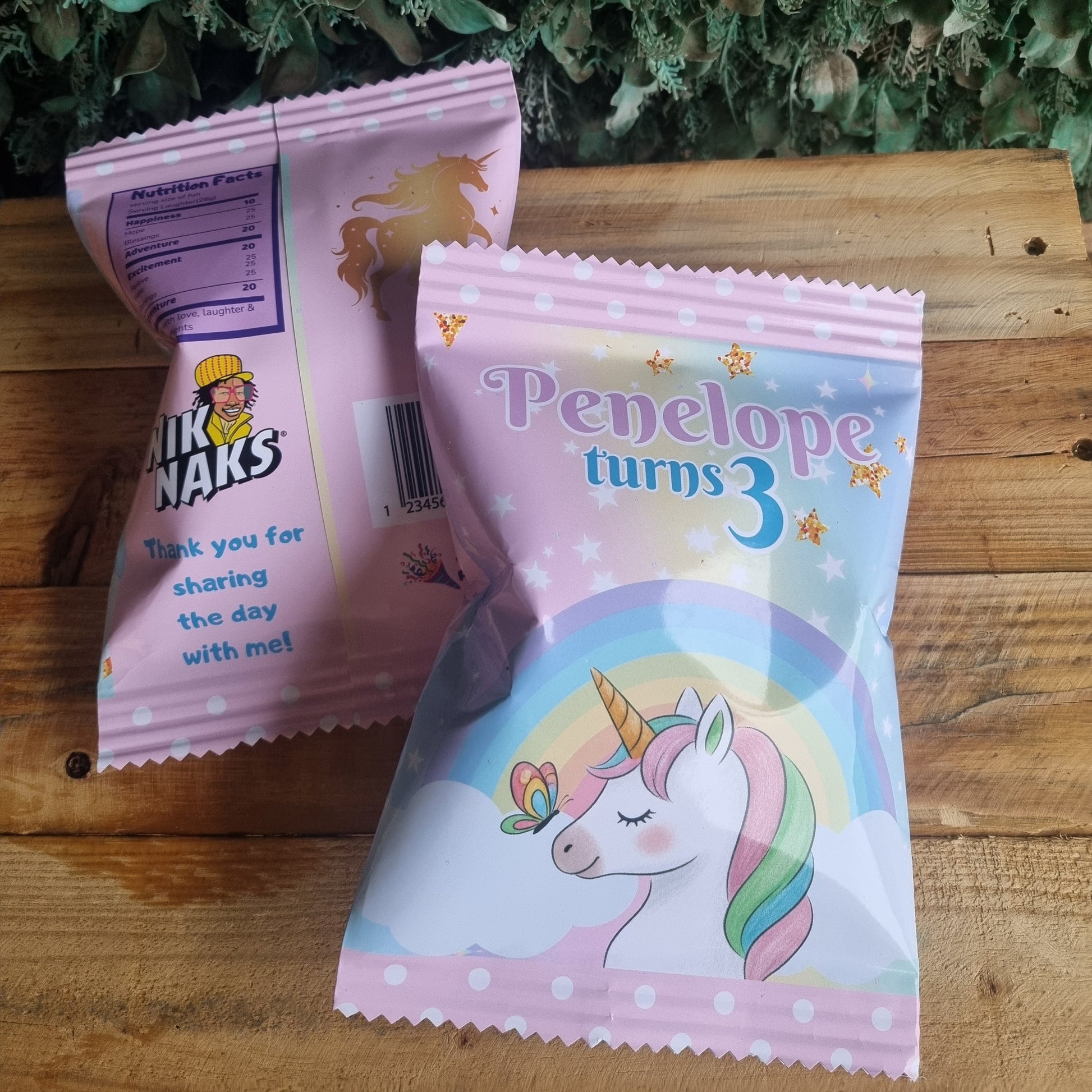 Two children's snack packages on a wooden surface with greenery in the background