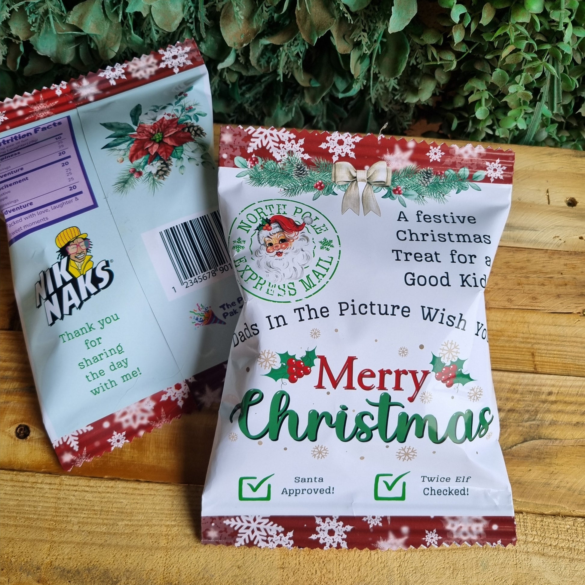 Two Christmas-themed packages on a wooden surface with greenery in the background