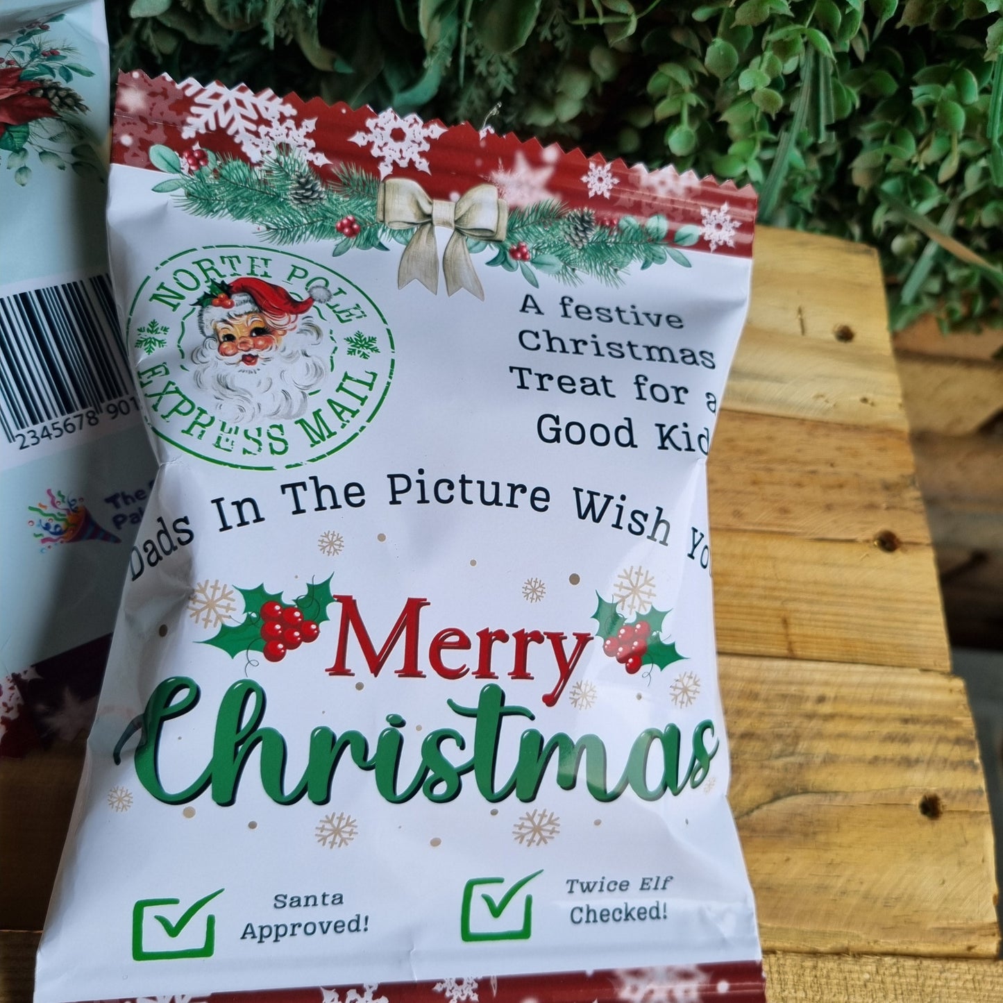 Christmas-themed treat package on a wooden surface with greenery in the background