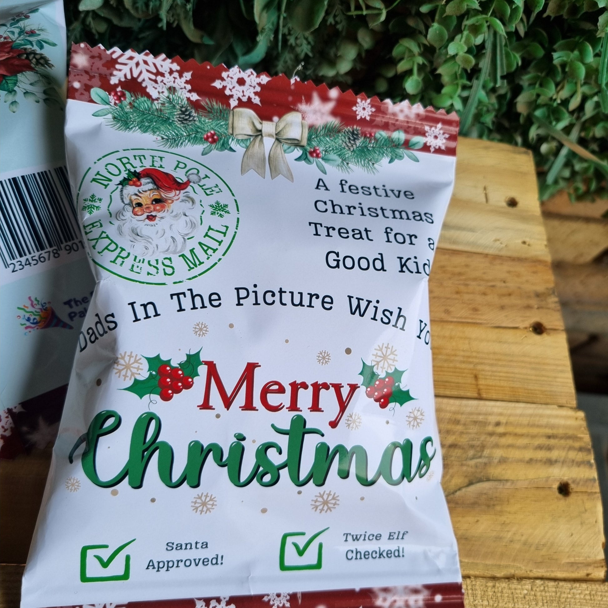 Christmas-themed treat package on a wooden surface with greenery in the background