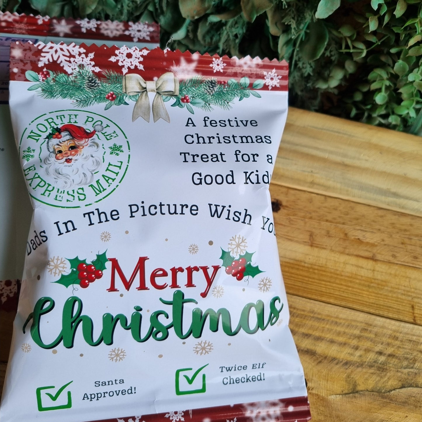 Christmas-themed product packaging on a wooden surface with greenery.