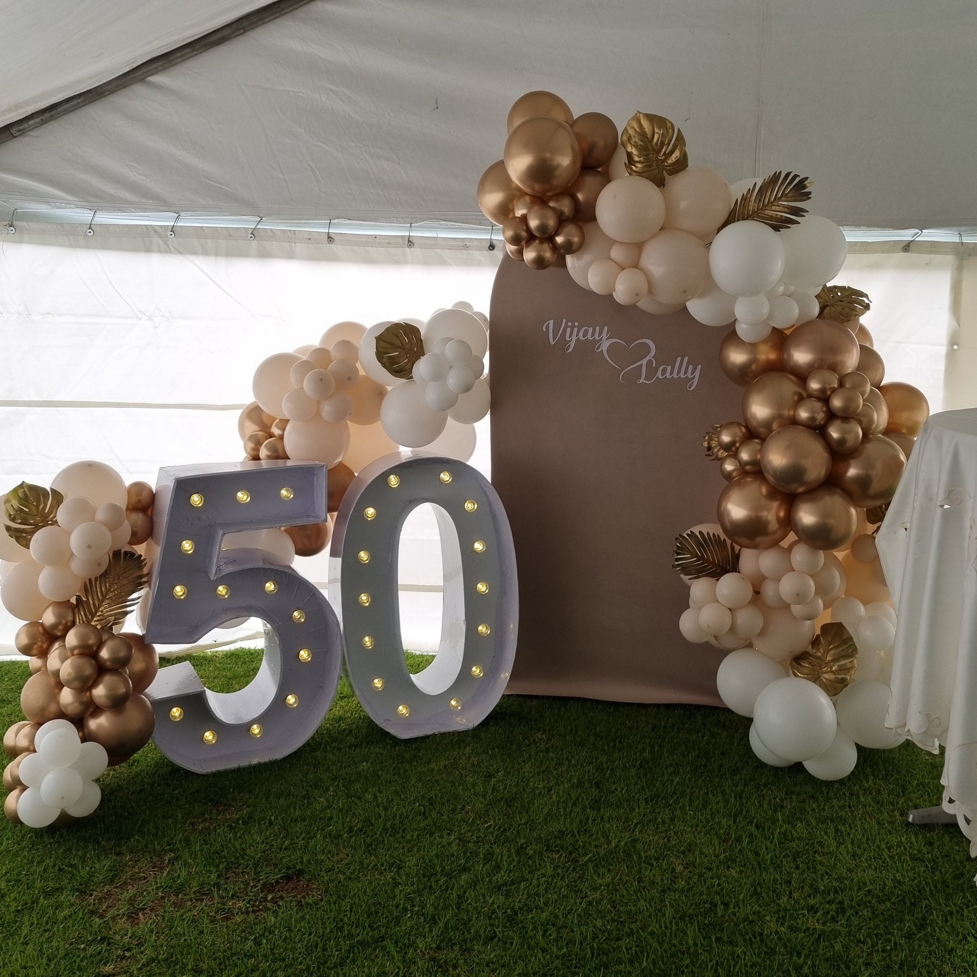 Decorative arch with balloons and '50' sign at an outdoor event.