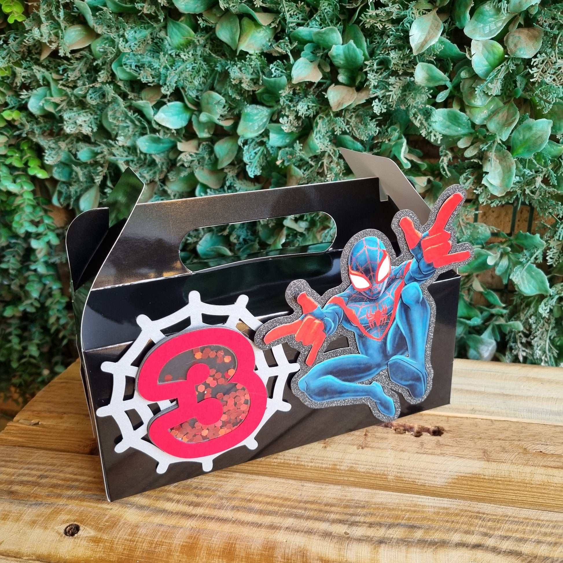 Decorative item with a spider design on a wooden surface and green foliage background