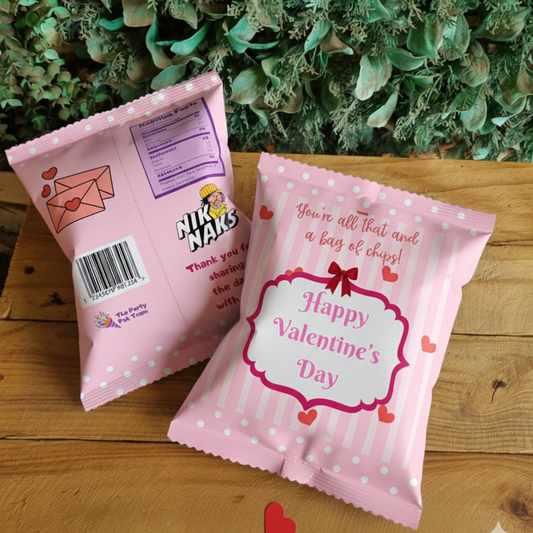 Two pink snack bags with Valentine's Day designs on a wooden surface with green foliage in the background.
