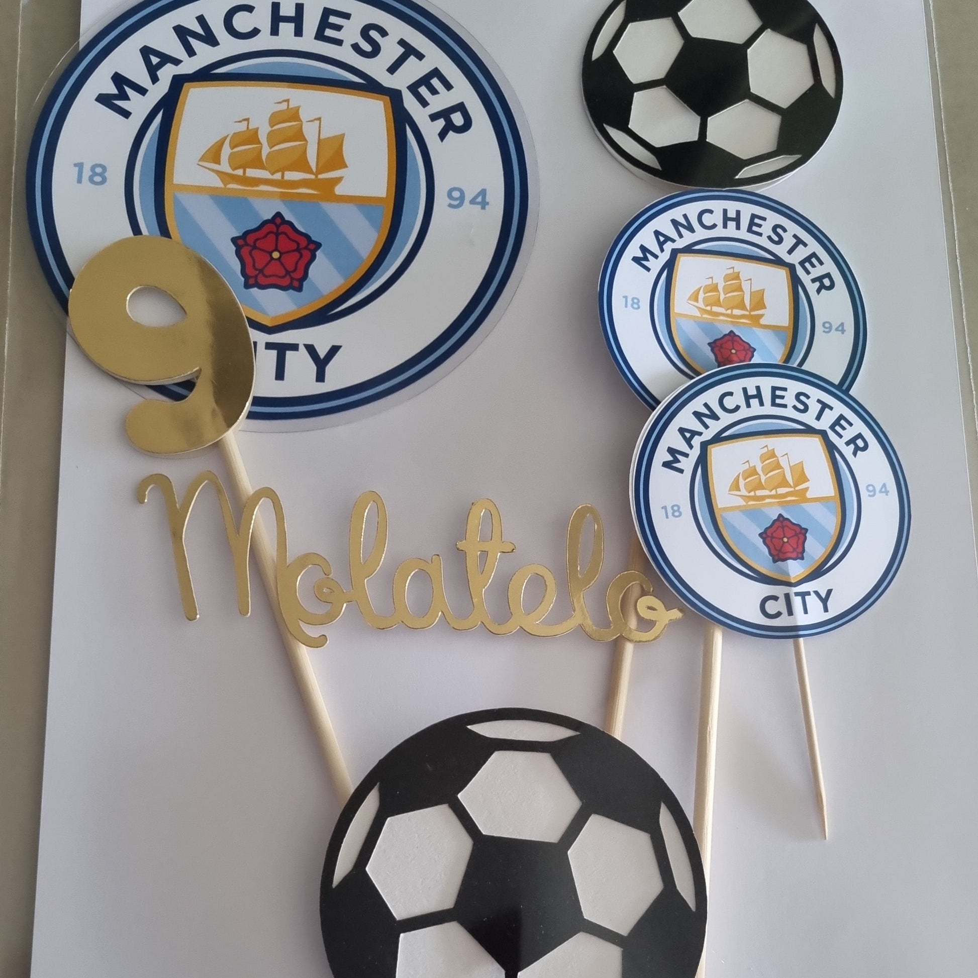 Soccer-themed cupcake toppers with Manchester City logo on a white sheet of paper.