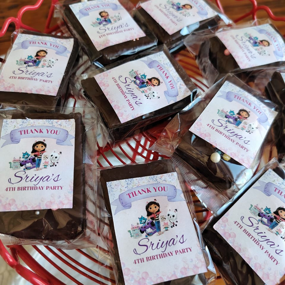 Chocolate bars with personalized labels for a birthday party on a red basket.